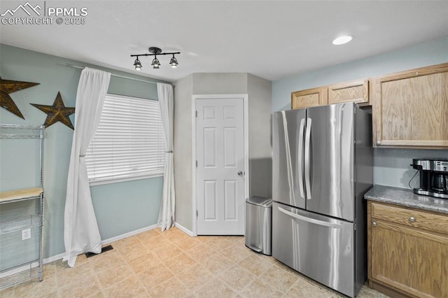 kitchen with dark countertops, visible vents, freestanding refrigerator, light brown cabinets, and baseboards