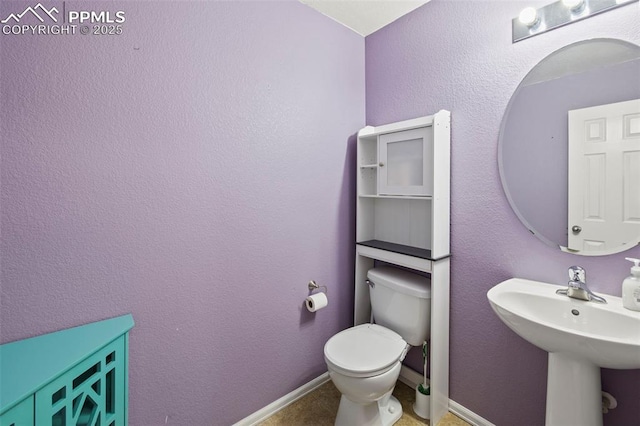 bathroom with toilet, baseboards, and a sink