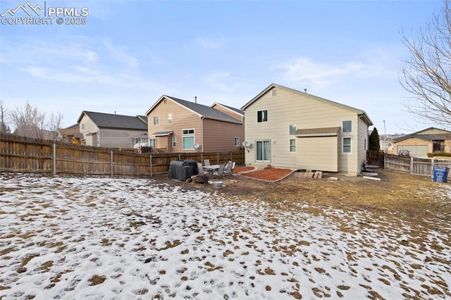 snow covered house featuring a residential view and a fenced backyard