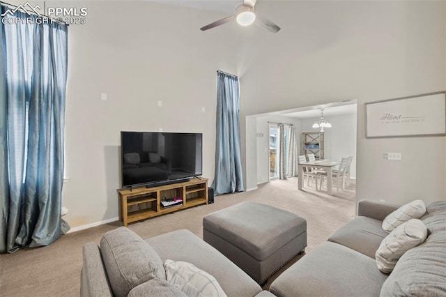 living room featuring light carpet, a towering ceiling, baseboards, and ceiling fan with notable chandelier