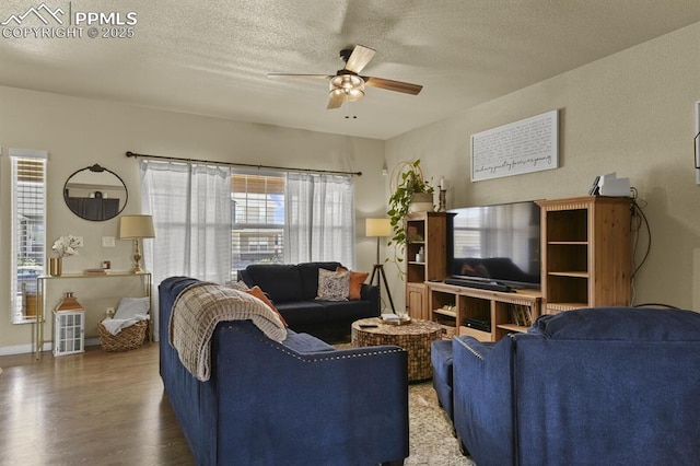 living area with a ceiling fan, a textured ceiling, baseboards, and wood finished floors