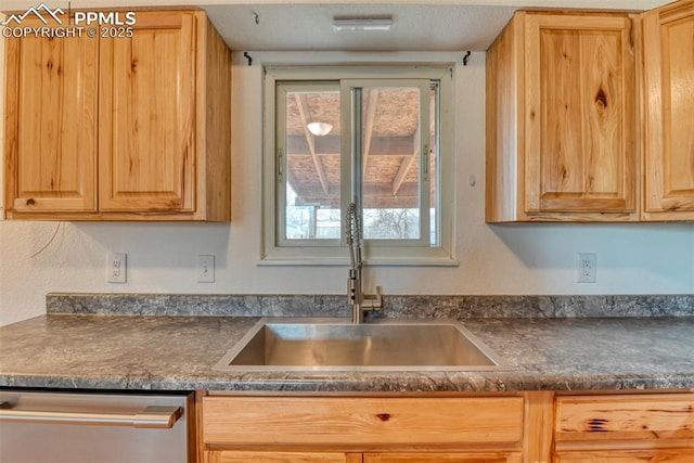 kitchen with dark countertops, dishwasher, a sink, and light brown cabinetry