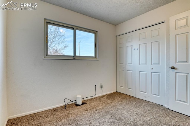 unfurnished bedroom featuring carpet floors, a closet, a textured ceiling, and baseboards