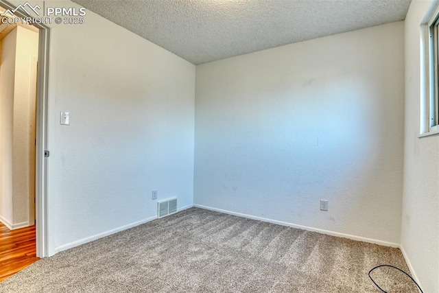 spare room featuring baseboards, a textured ceiling, visible vents, and carpet flooring