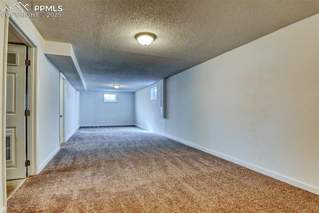 empty room featuring carpet, a textured ceiling, visible vents, and baseboards