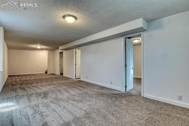 basement with light colored carpet, a textured ceiling, and baseboards