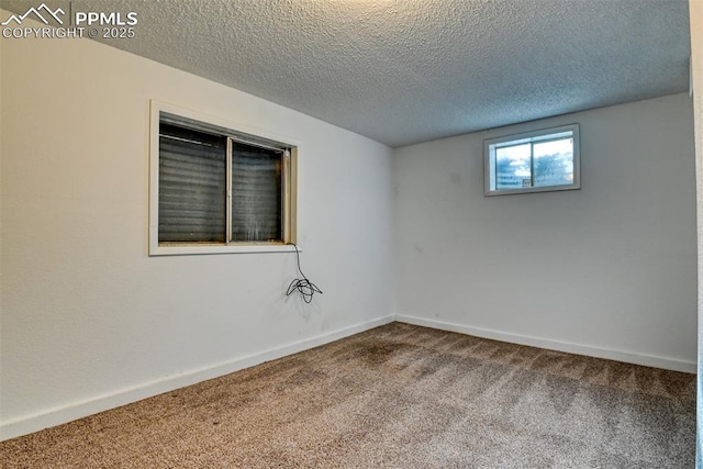 carpeted spare room featuring a textured ceiling and baseboards