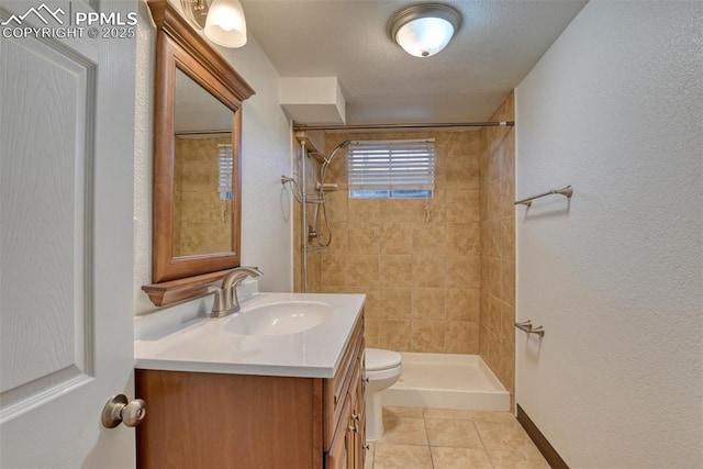 full bathroom with toilet, vanity, baseboards, a tile shower, and tile patterned floors