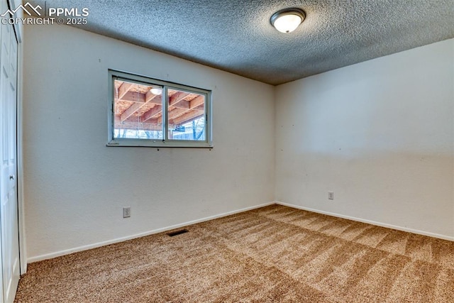 carpeted spare room featuring visible vents, baseboards, and a textured ceiling