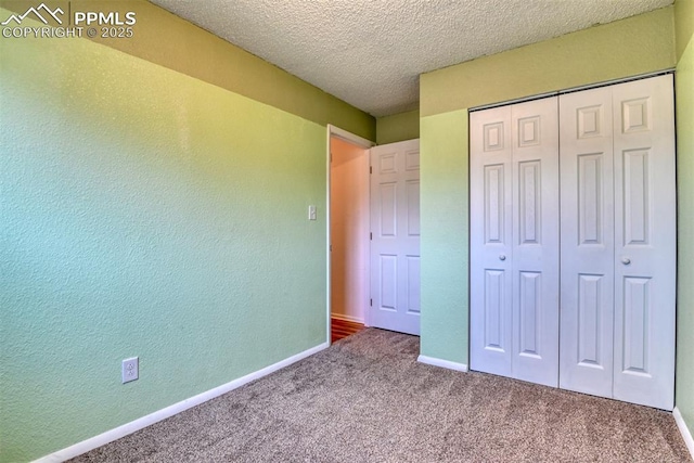 unfurnished bedroom featuring carpet floors, baseboards, a closet, and a textured wall