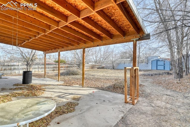 view of patio with an outbuilding, a storage unit, and fence