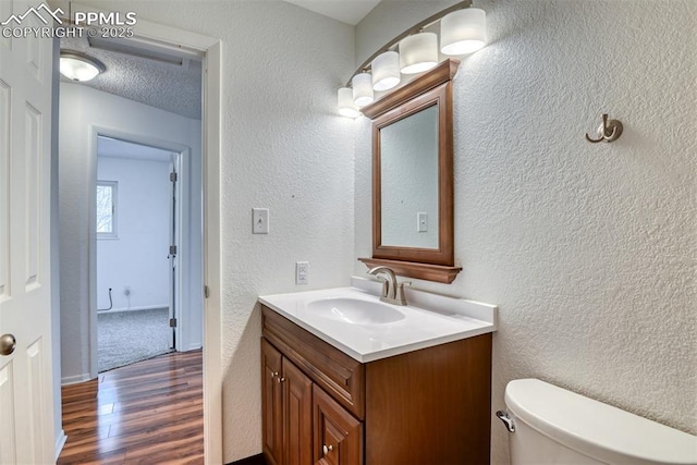 bathroom with a textured ceiling, a textured wall, wood finished floors, and vanity