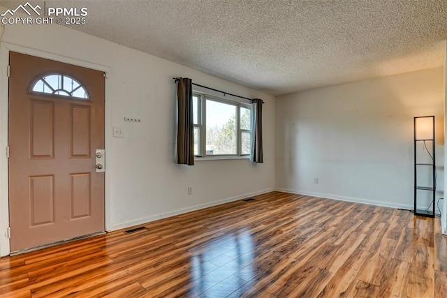 entrance foyer with visible vents, a textured ceiling, baseboards, and wood finished floors