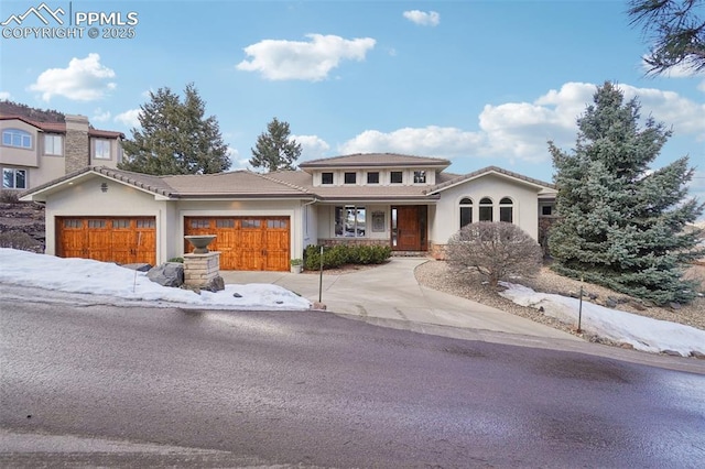 view of front of house featuring a tiled roof, an attached garage, and stucco siding