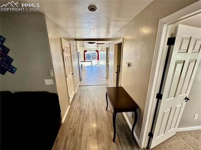 hallway featuring baseboards and wood finished floors