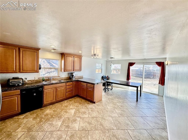 kitchen with black dishwasher, dark countertops, brown cabinets, a peninsula, and a sink