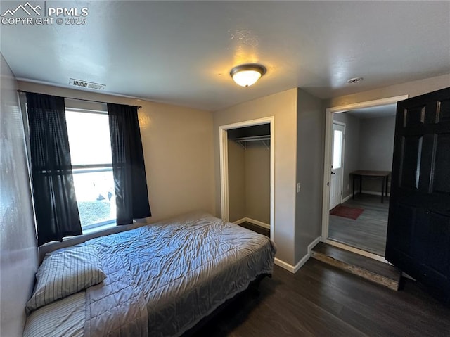 bedroom featuring baseboards, multiple windows, visible vents, and wood finished floors