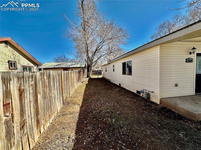 view of side of home featuring crawl space and fence