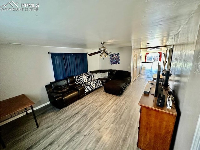 living room with ceiling fan, baseboards, and wood finished floors