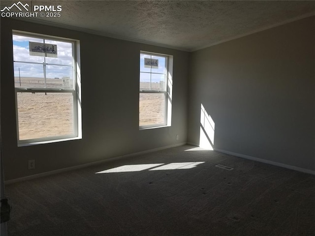 empty room featuring dark carpet, a textured ceiling, and baseboards