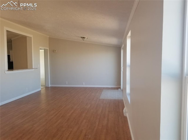 spare room featuring a textured ceiling, baseboards, and wood finished floors