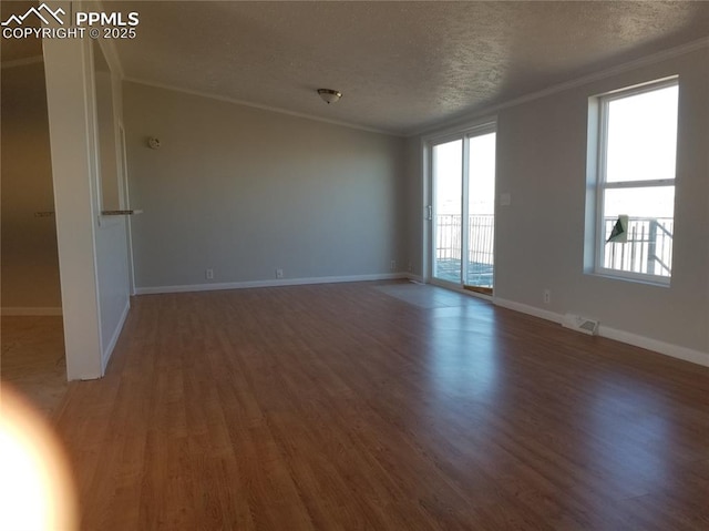 empty room featuring plenty of natural light, dark wood-style flooring, crown molding, and a textured ceiling