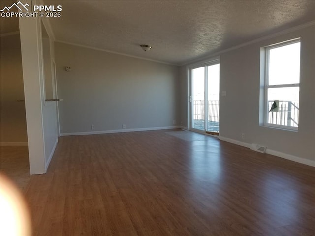 spare room with ornamental molding, dark wood-type flooring, visible vents, and a healthy amount of sunlight