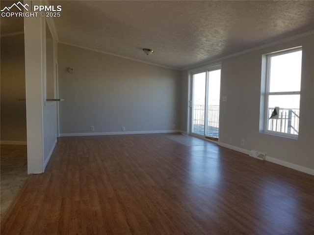 spare room with a healthy amount of sunlight, a textured ceiling, ornamental molding, and dark wood-type flooring