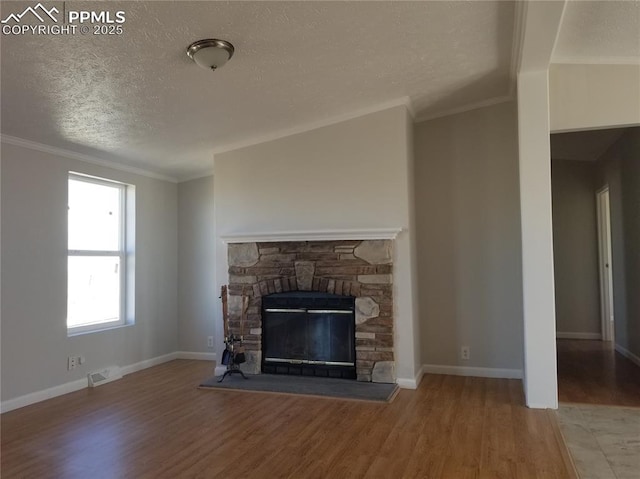 unfurnished living room featuring baseboards, visible vents, a textured ceiling, light wood-type flooring, and a fireplace