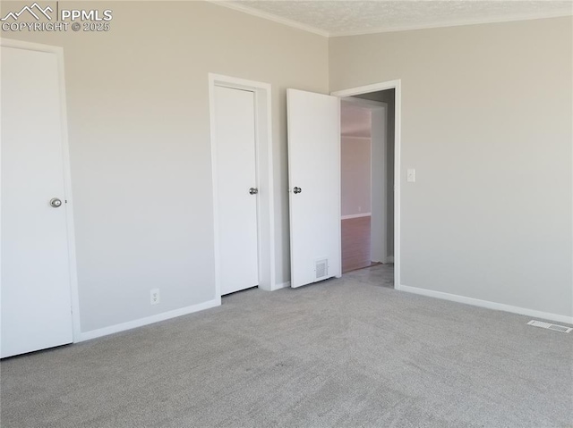 unfurnished bedroom featuring visible vents, ornamental molding, light carpet, a textured ceiling, and baseboards