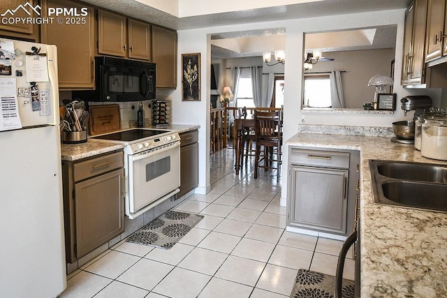 kitchen with light tile patterned floors, white appliances, a sink, and a notable chandelier