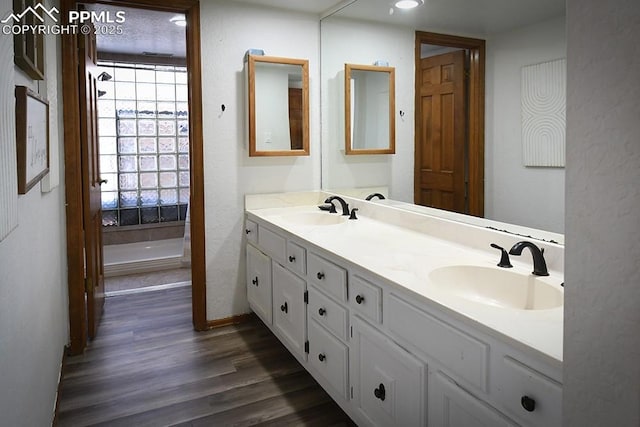 bathroom with double vanity, a sink, and wood finished floors