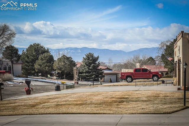 view of yard featuring concrete driveway, a mountain view, and an attached garage