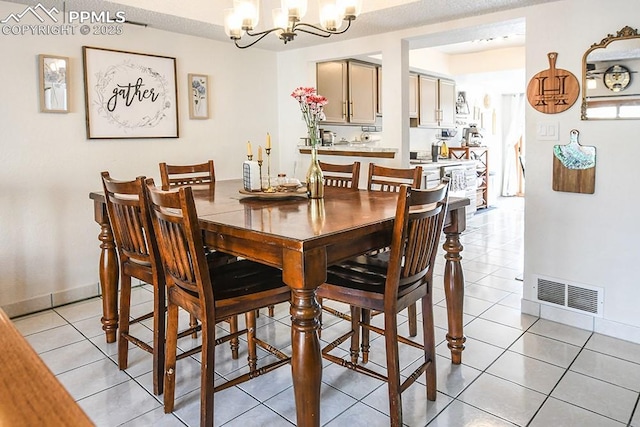 dining space featuring a chandelier, visible vents, baseboards, and light tile patterned floors