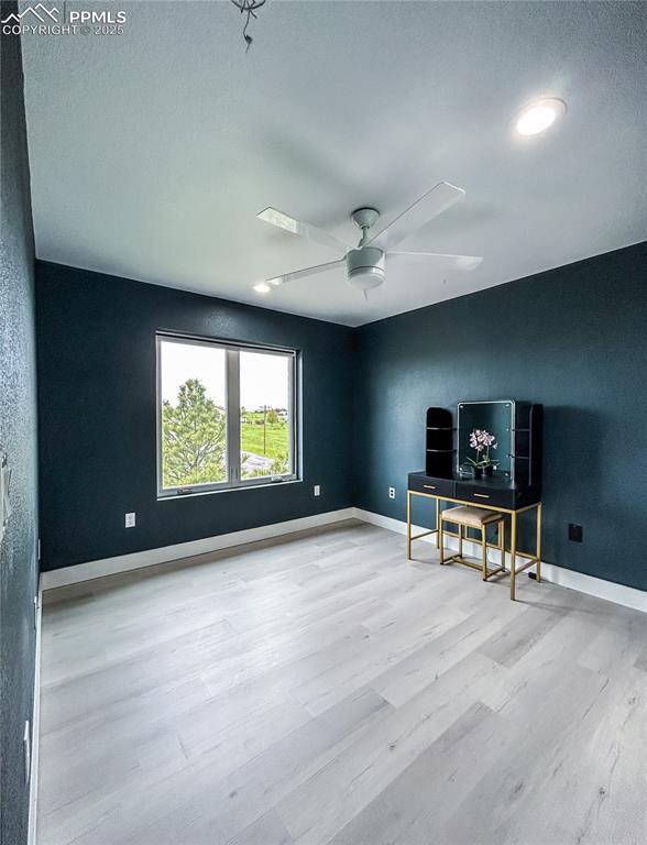 interior space featuring light wood-type flooring, ceiling fan, and baseboards