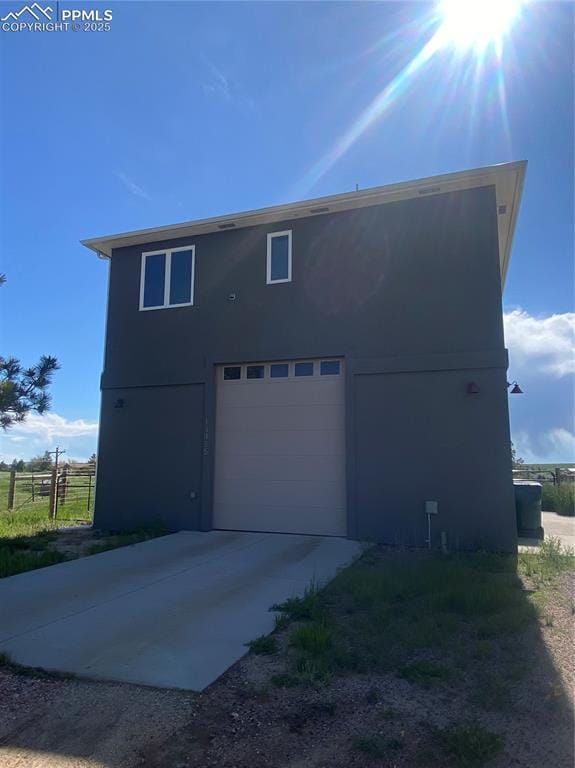 view of side of property with a garage, driveway, and fence