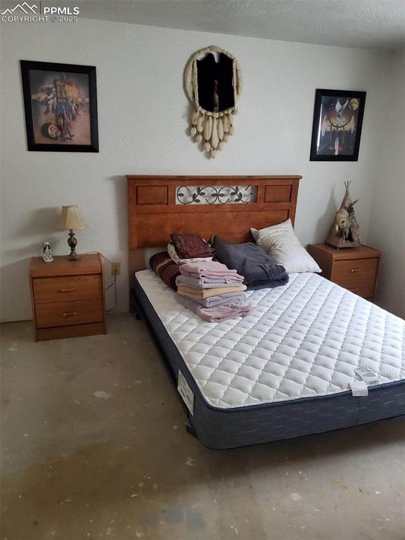 bedroom with a textured ceiling and concrete floors