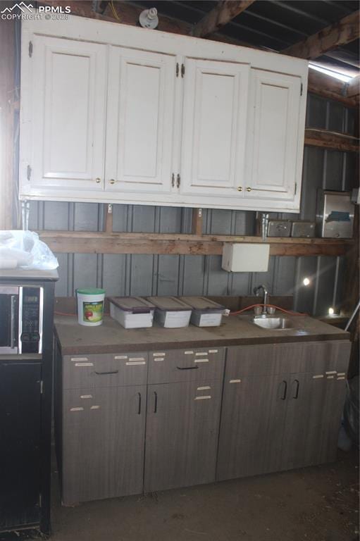 kitchen with concrete floors, white cabinetry, and a sink