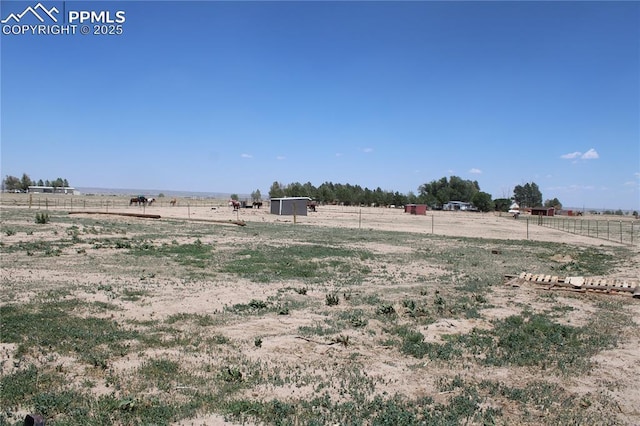 view of yard with fence and a rural view