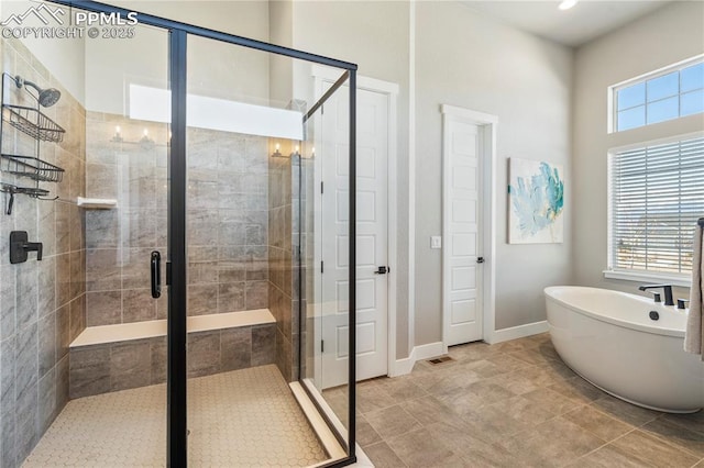 full bath featuring a soaking tub, a shower stall, and baseboards