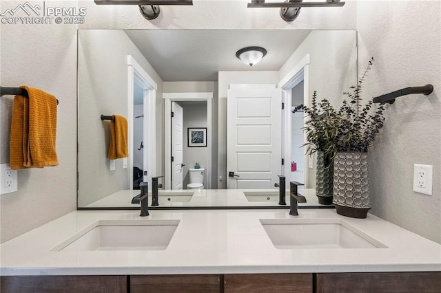 bathroom featuring double vanity, a sink, and toilet