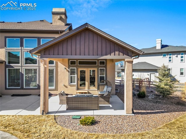 rear view of house with board and batten siding, french doors, a patio, and an outdoor living space