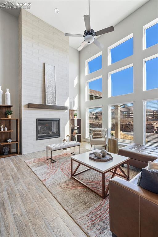 living area featuring a wealth of natural light, ceiling fan, a fireplace, and wood finished floors