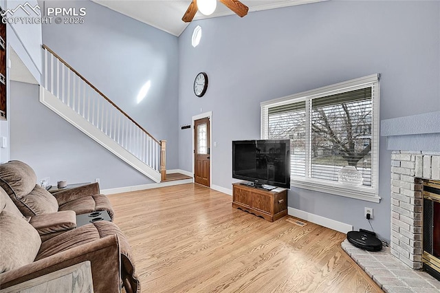 living room featuring visible vents, a brick fireplace, ceiling fan, stairway, and wood finished floors