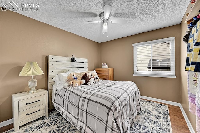bedroom featuring ceiling fan, wood finished floors, baseboards, and a textured ceiling