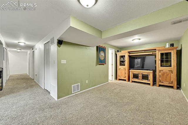 finished basement featuring visible vents, carpet flooring, a textured ceiling, and baseboards