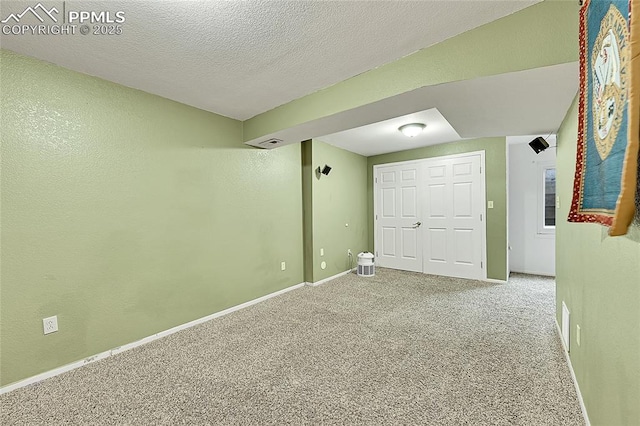 unfurnished room featuring visible vents, baseboards, carpet, a textured wall, and a textured ceiling
