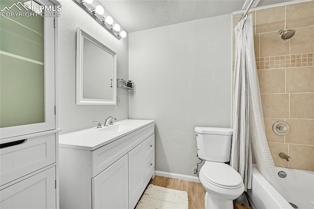 full bath with vanity, wood finished floors, baseboards, a textured ceiling, and toilet
