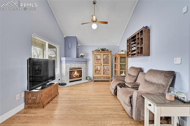 living area featuring crown molding, baseboards, ceiling fan, a fireplace, and wood finished floors