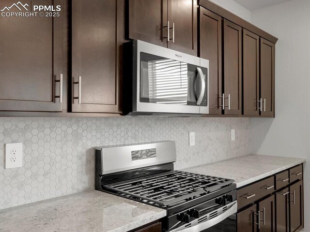 kitchen with backsplash, dark brown cabinetry, appliances with stainless steel finishes, and light stone counters